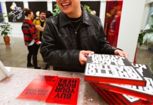 person in leather jacket smiling as they buy Ghetto Gastro Black Power Kitchen book