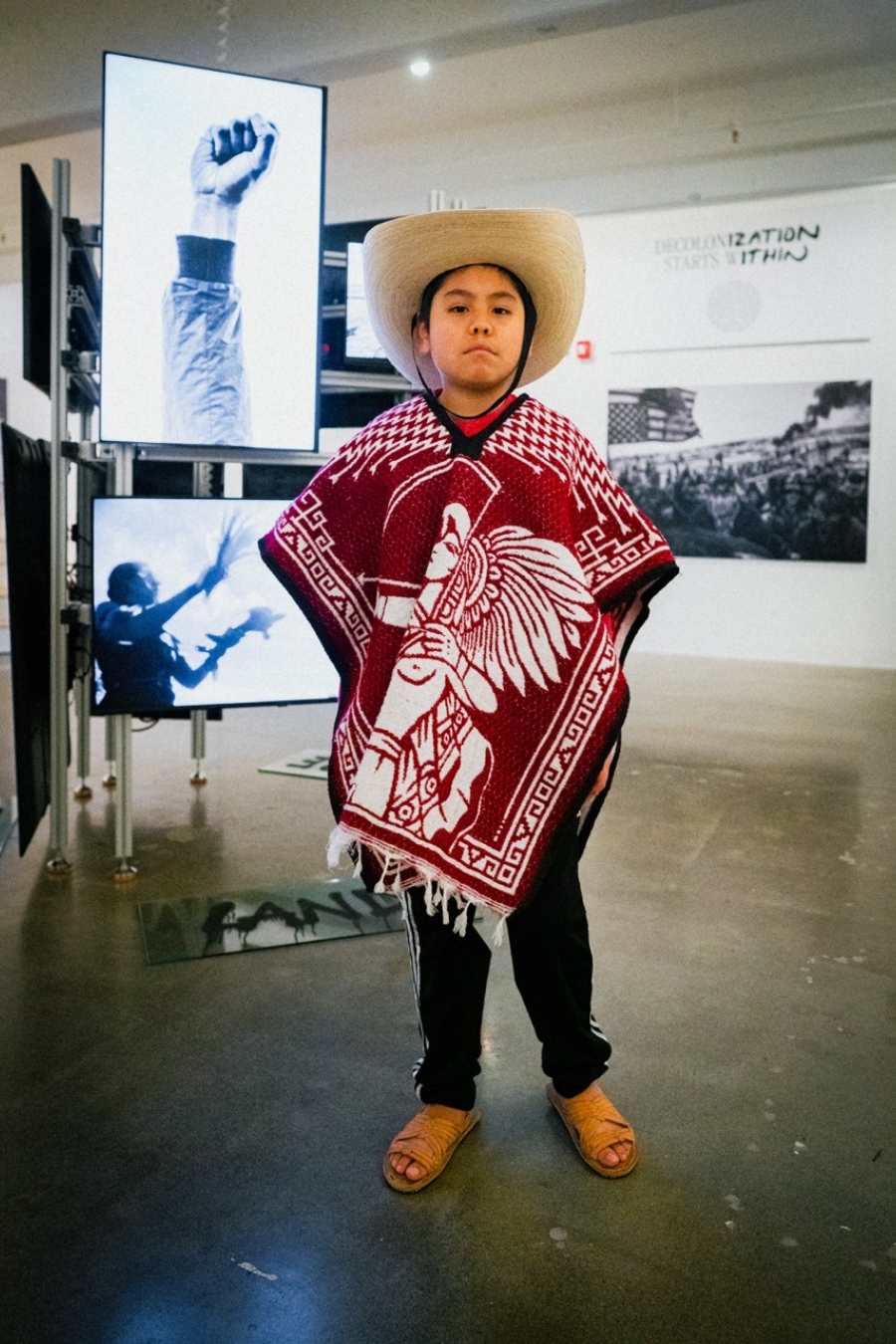 child wears traditional mexican hat, jacket and boots at gallery opening
