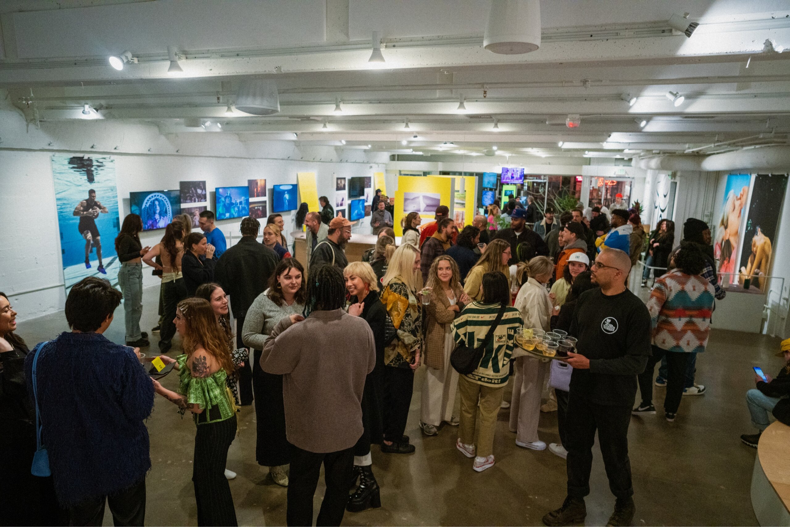 Gallery full of people having drinks and conversation at show opening party