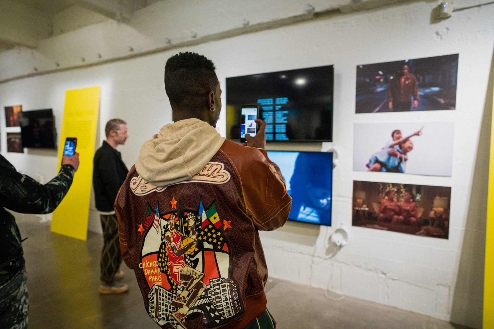 2 people take photos with their phones at gallery opening