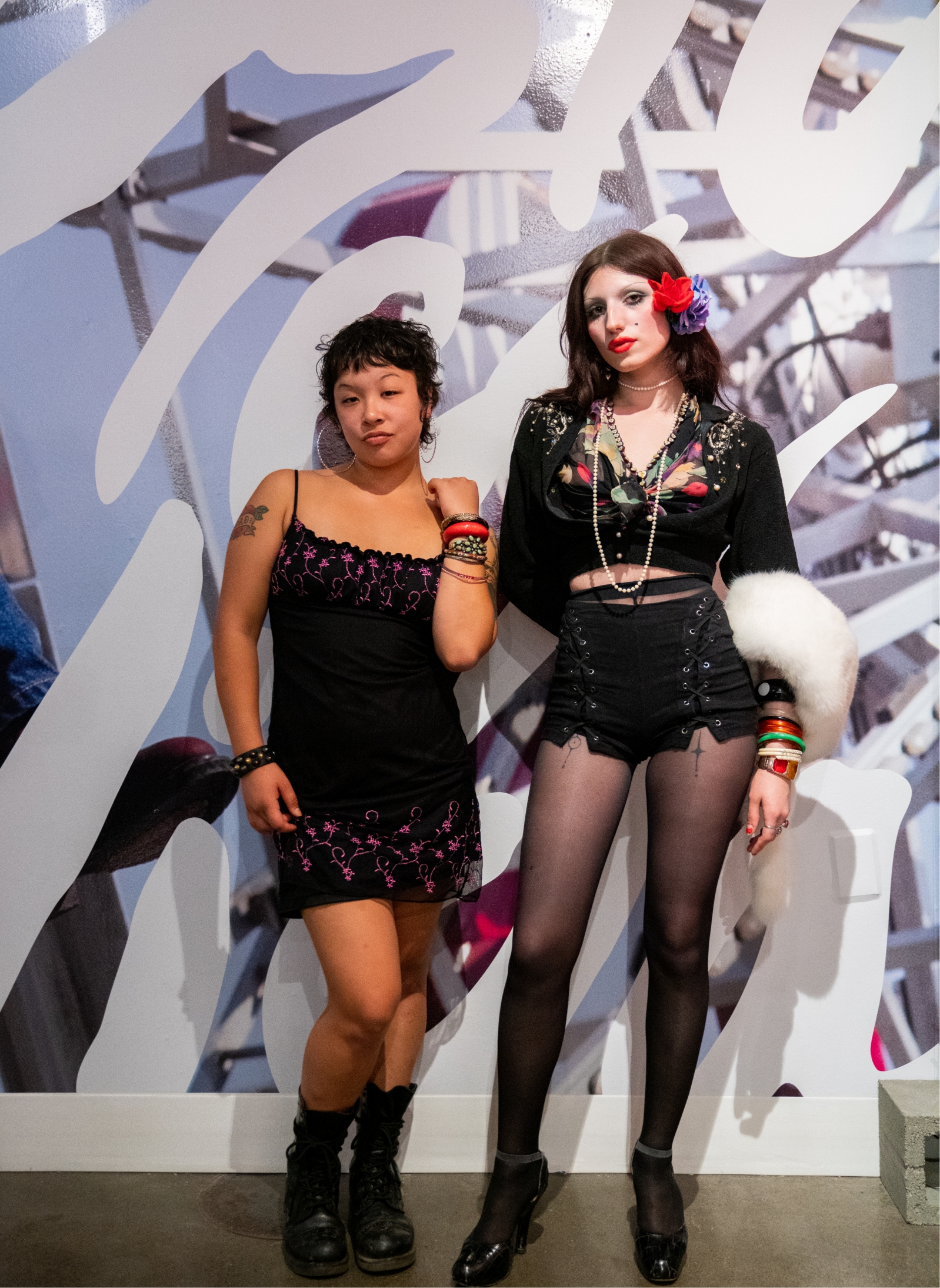 2 people stand together in front of gallery wall