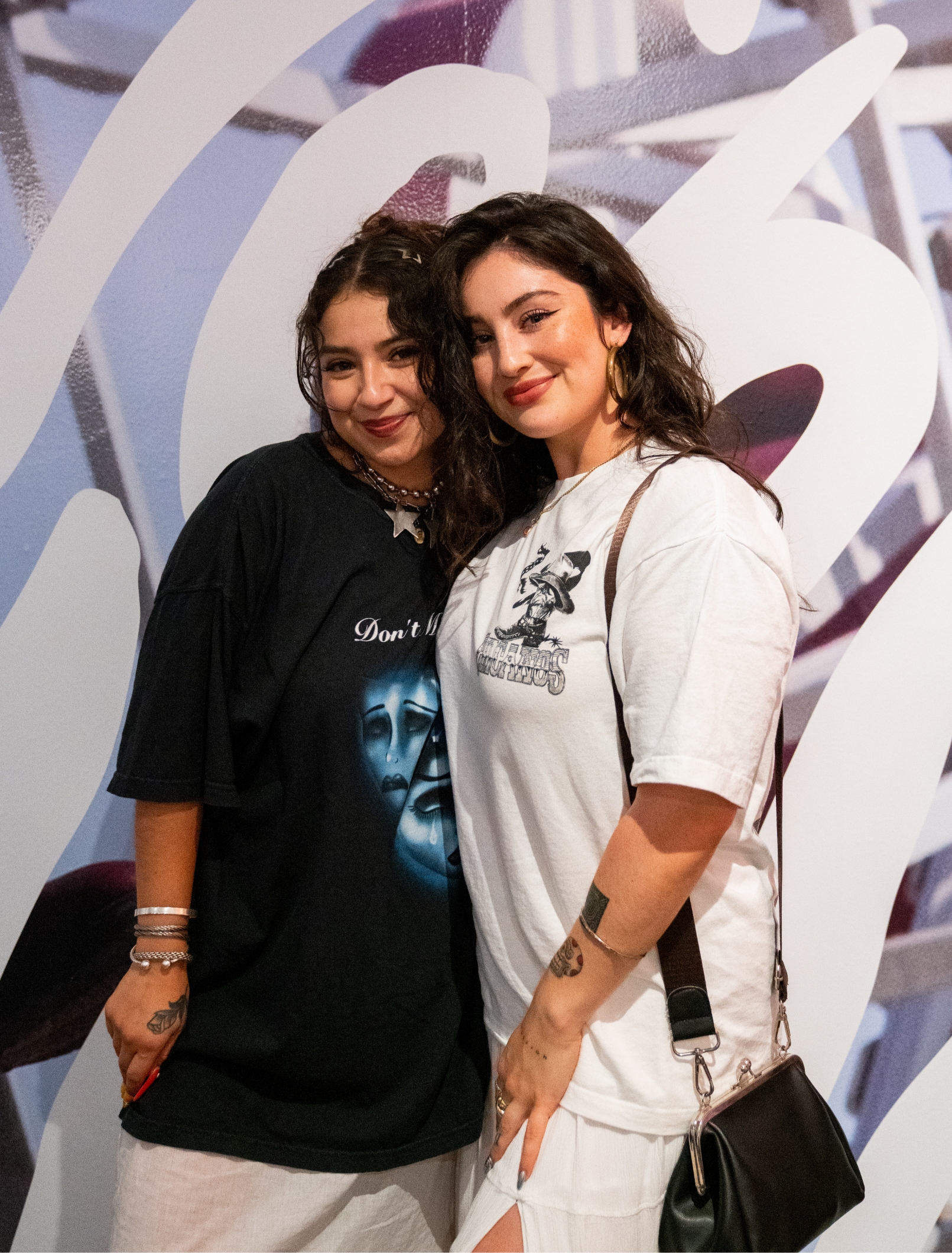 2 women pose together smiling in front of gallery wall