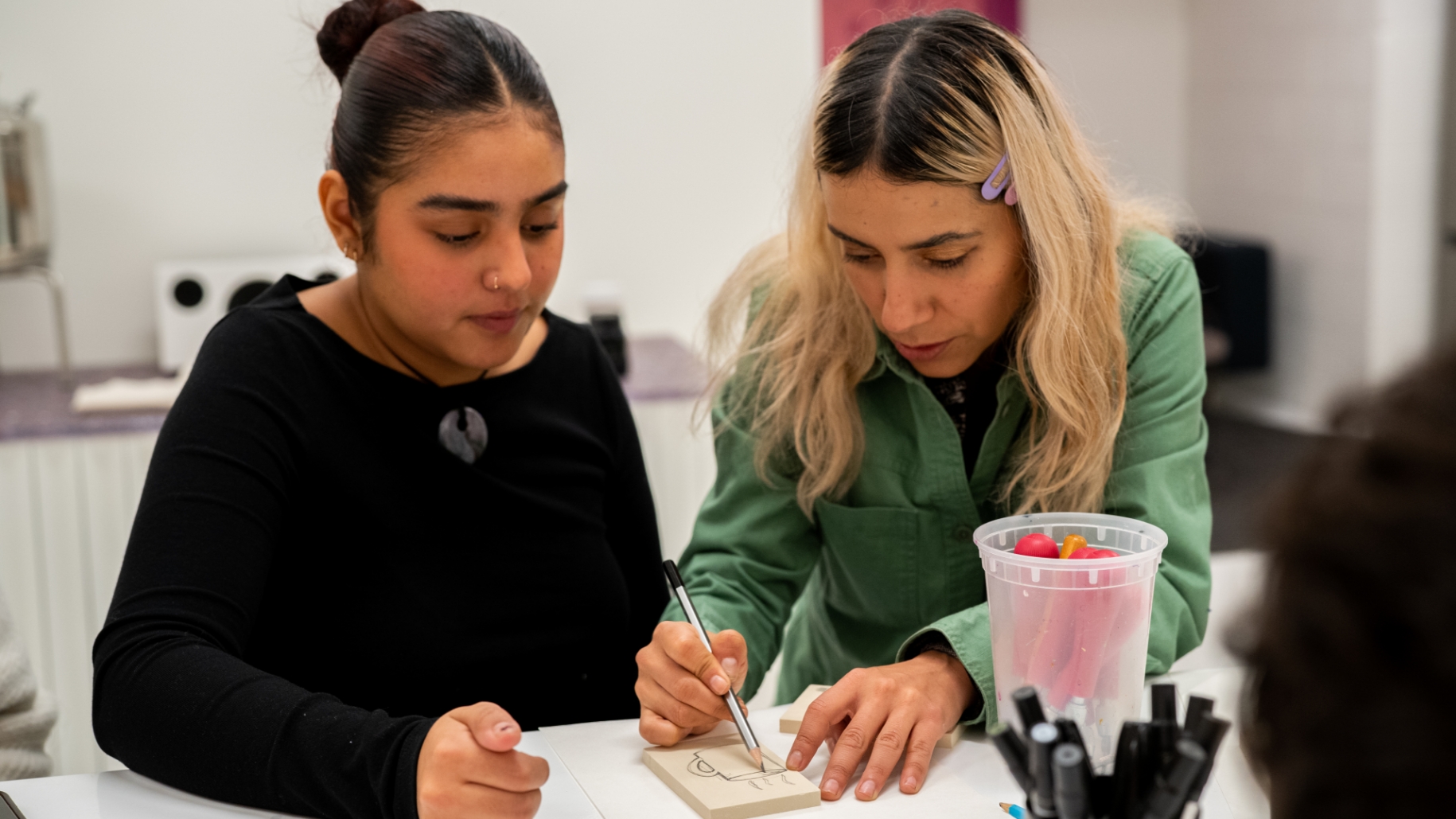 Two women working at a table in a workshop.