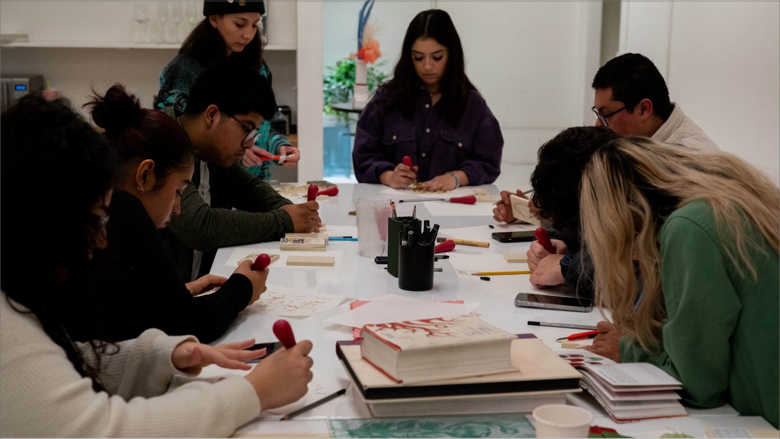 A group of people sitting around a table with paper and pencils.