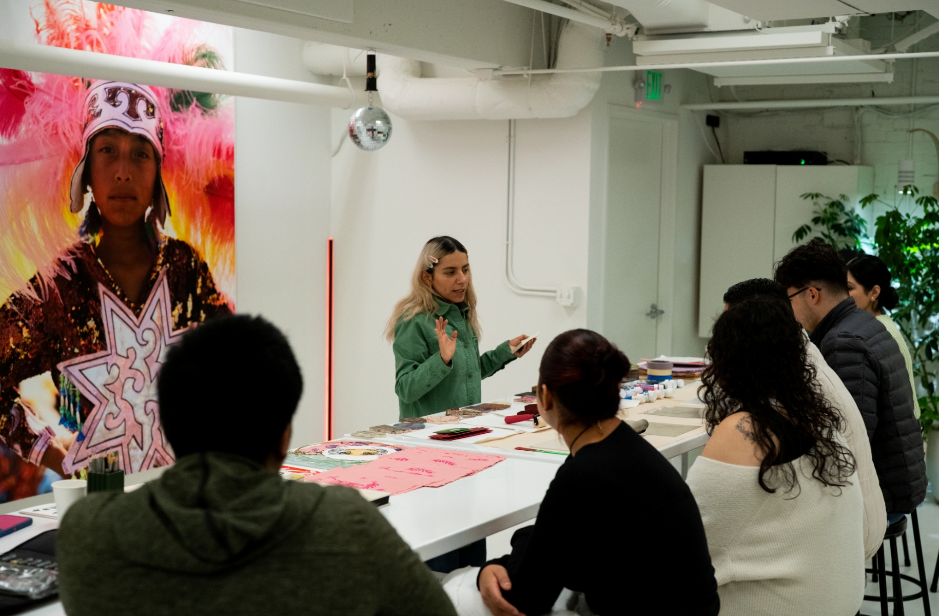 A group of people sitting at a table in front of a painting.