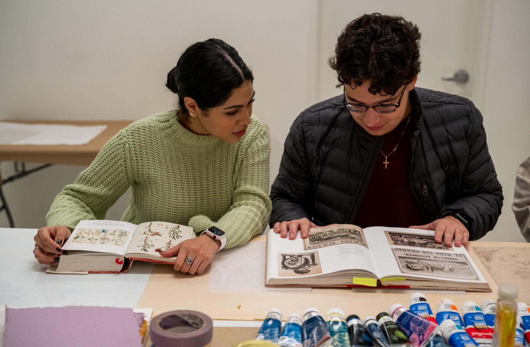 Two people sitting at a table looking at a book.