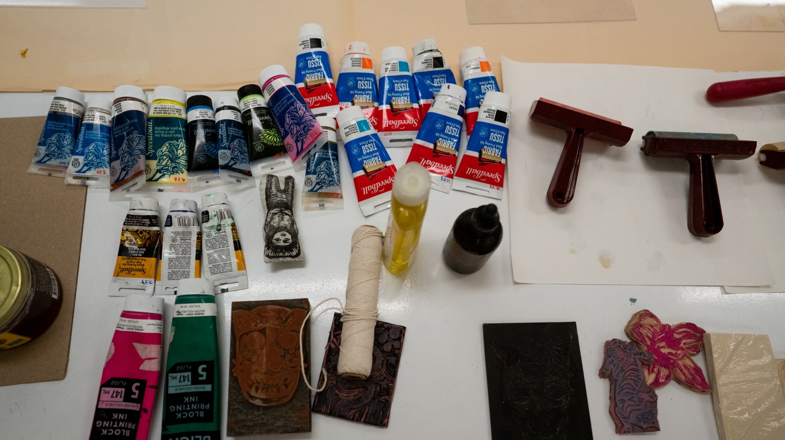 A table with a variety of paints and brushes on it.