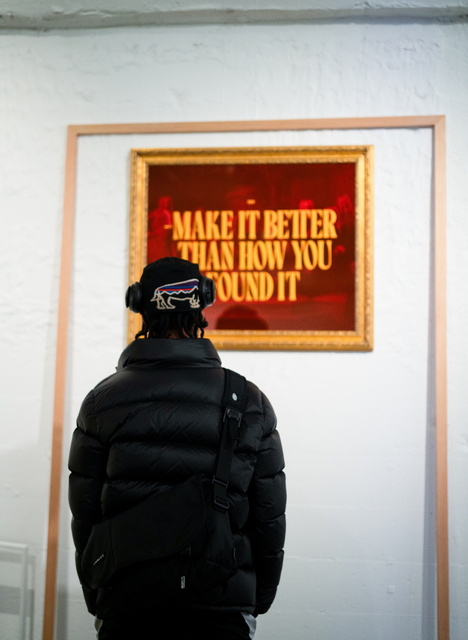A man looking at a framed poster that says make it better than how you could.
