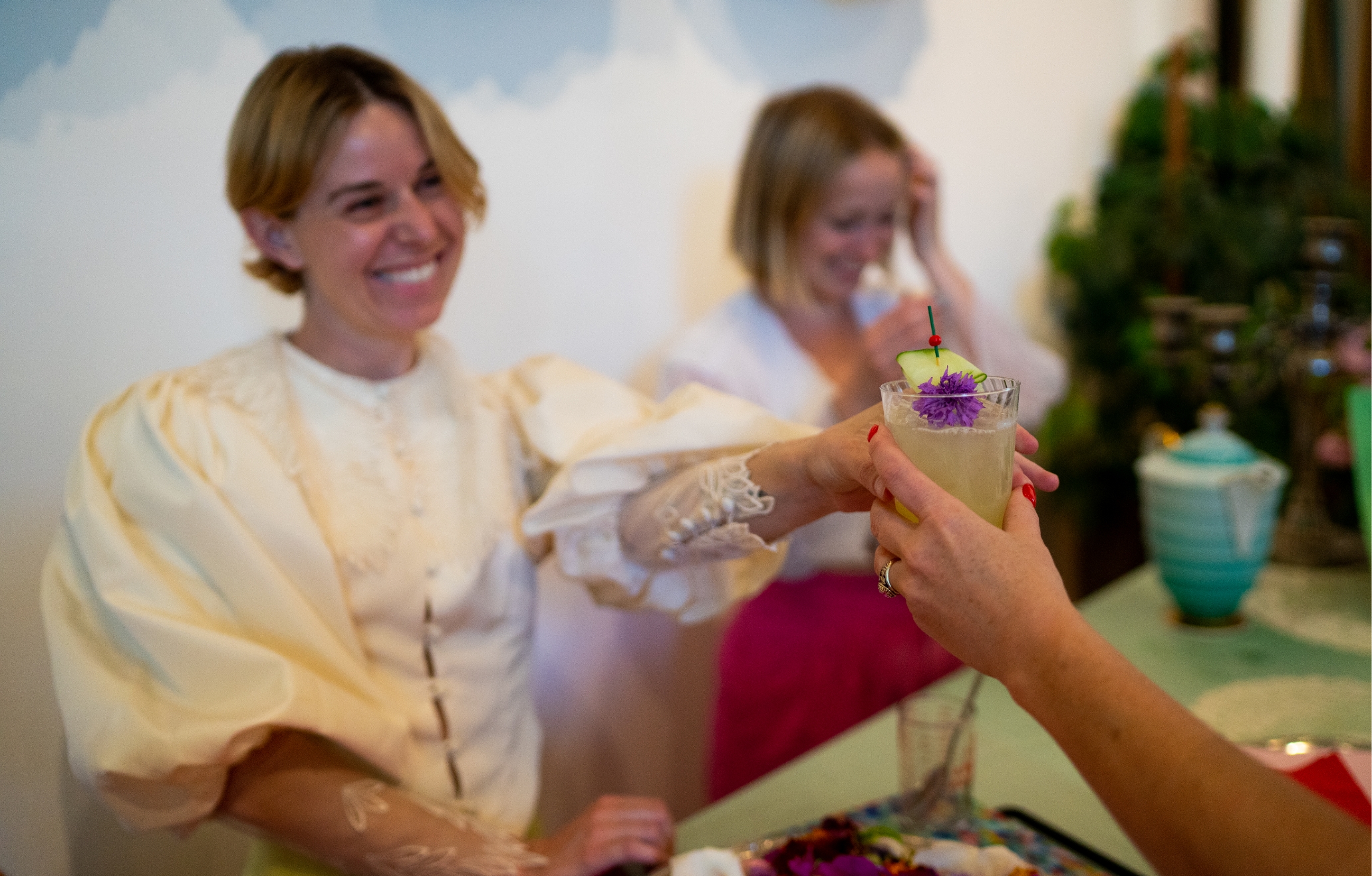 A woman in a white dress is holding a glass of drink.