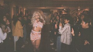 A woman in a garment dancing with a crowd of people.