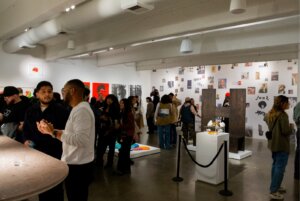 large group of people look at art and socialize in art gallery space during opening event