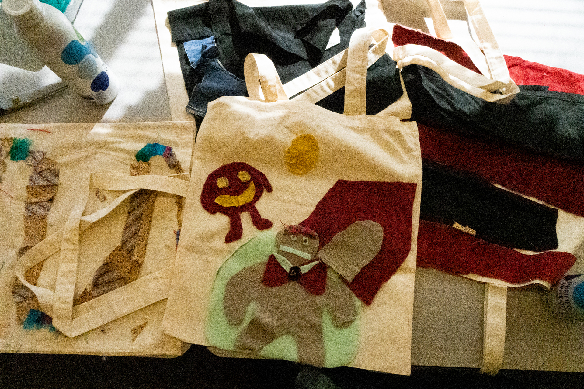 tote bags with fabric designs sewn and glued onto them