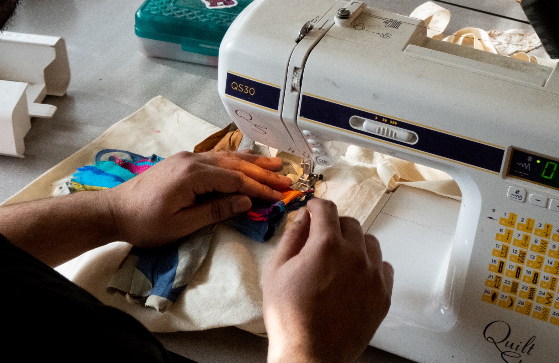 two hands guide fabric through sewing machine