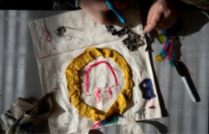 a happy face design on a tote bag with someone cutting fabric