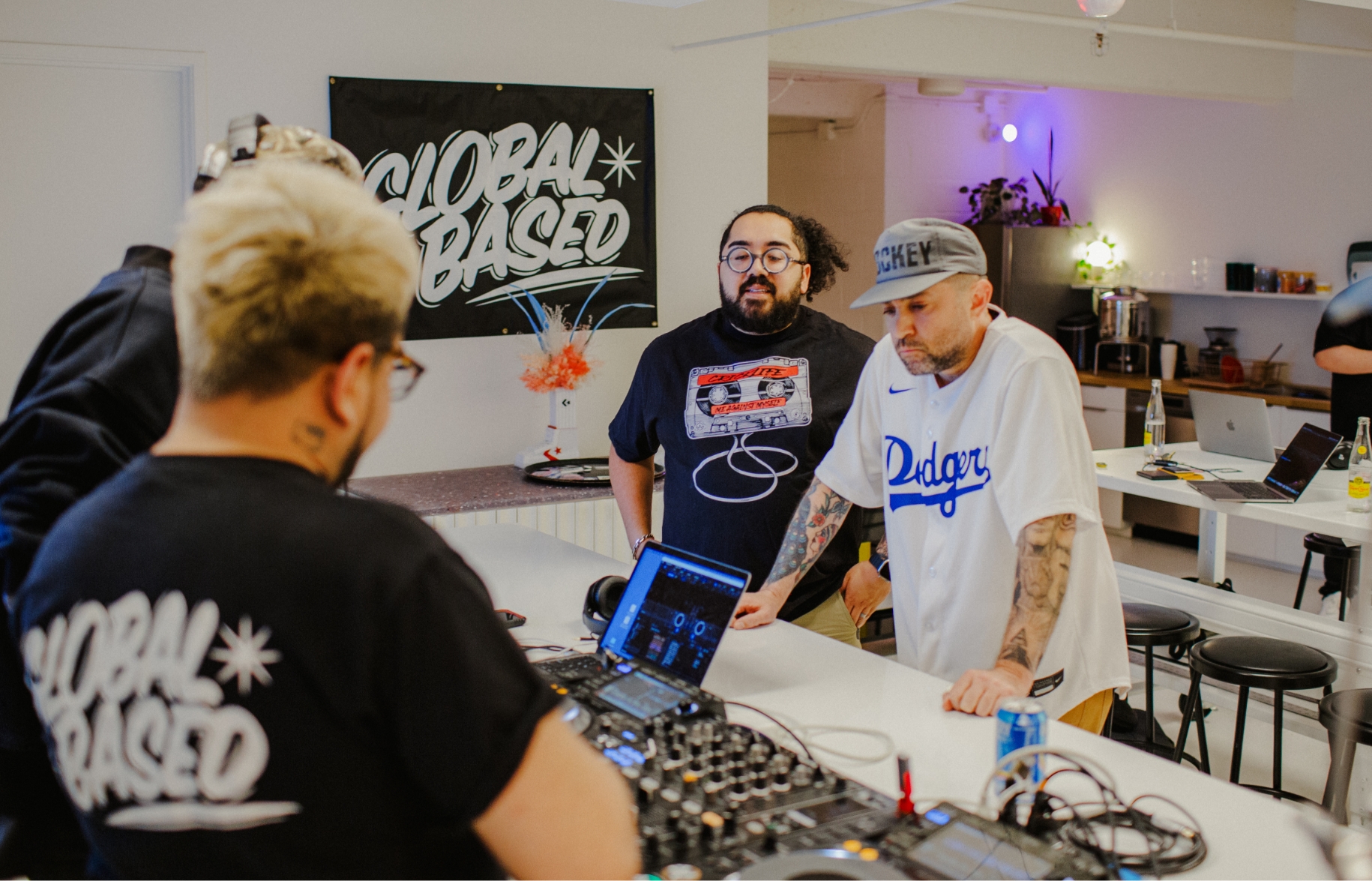 3 people standing around a laptop and DJ mixer
