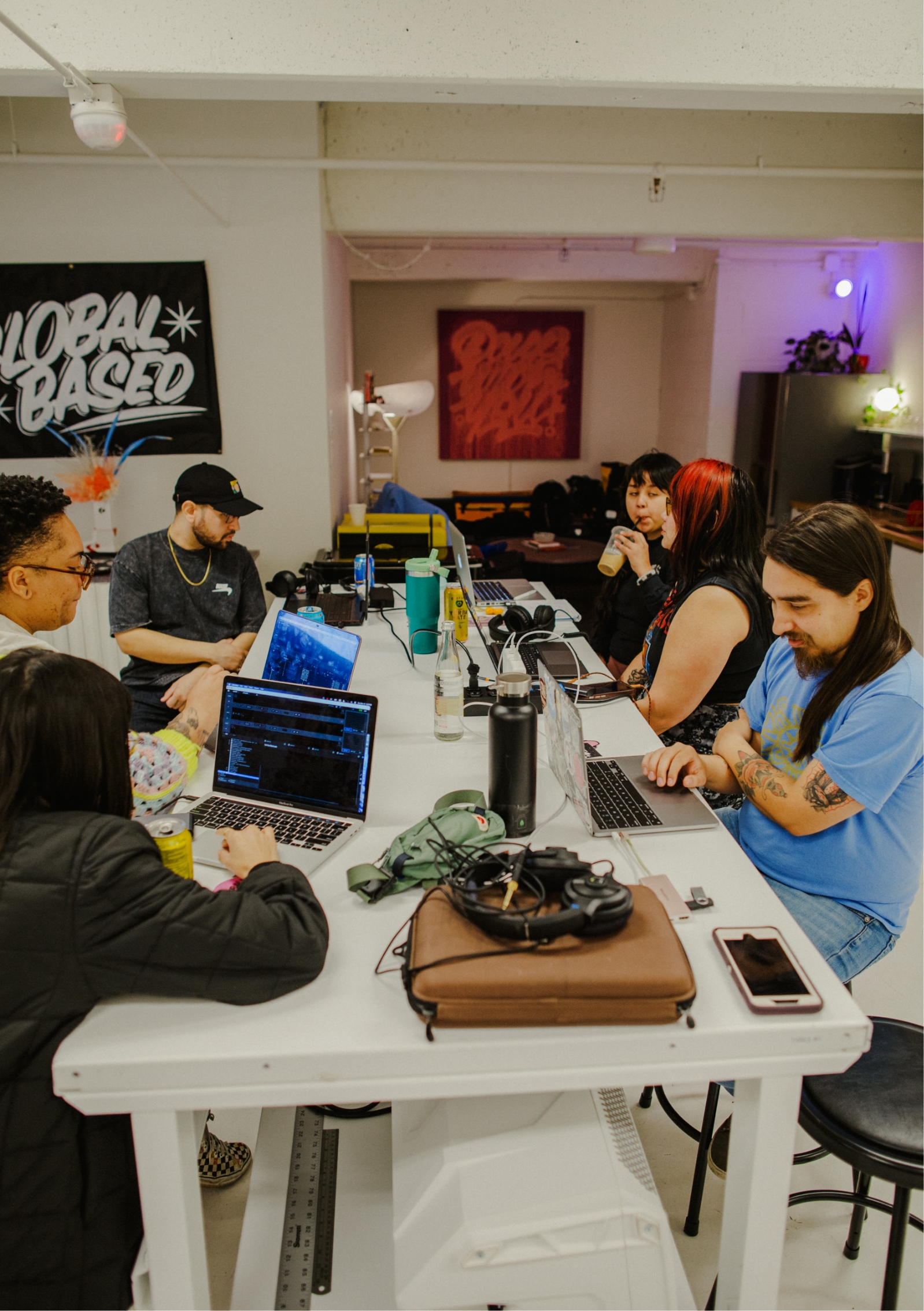 People sit around large white table working on laptops