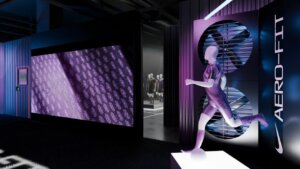 A mannequin in athletic gear poses in front of a neon Aero-Fit sign and a large digital screen, with more mannequins visible in the background.