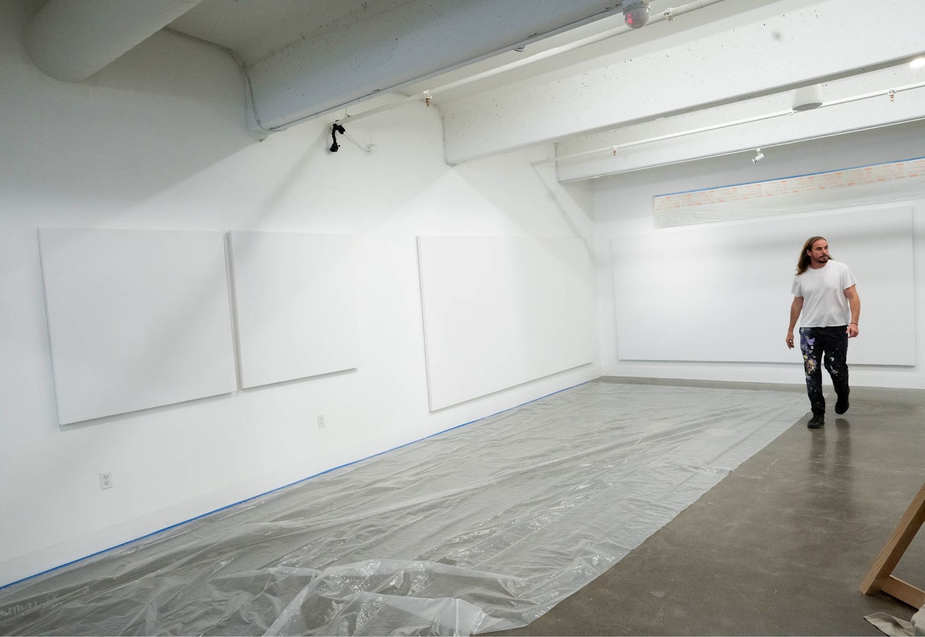 Mark (MadSteez) in gallery with all white walls. Plastic drop cloth on floor
