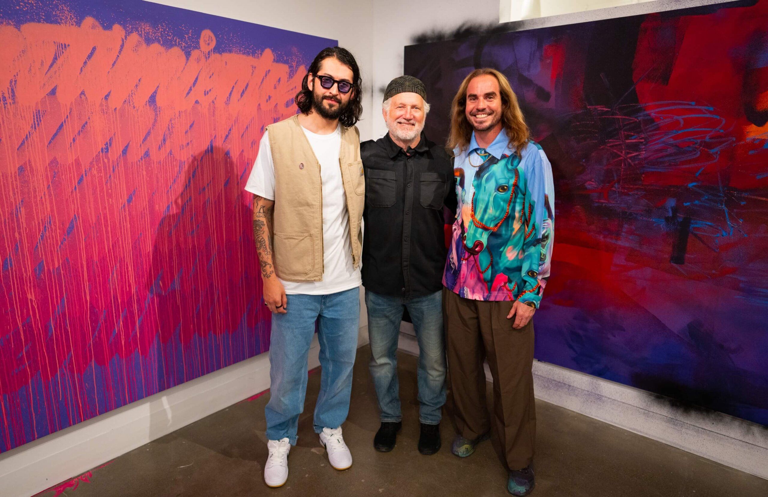 Madsteez and Its a Living pose with Tinker Hatfield in front their paintings