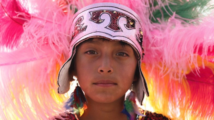 young person in brightly coloured feathered head dress