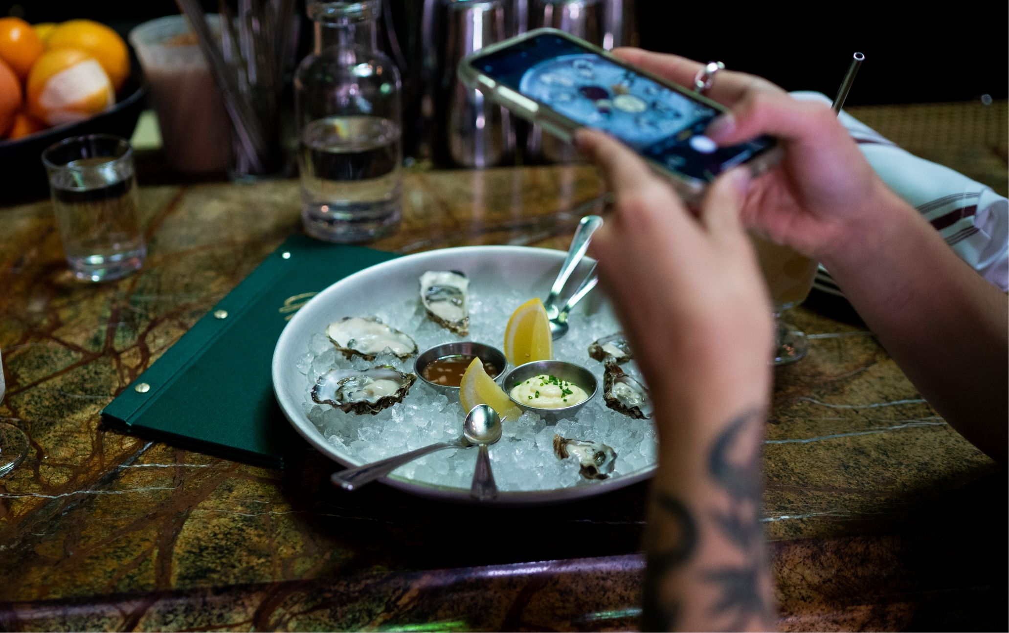 A person taking a picture of a plate of oysters.