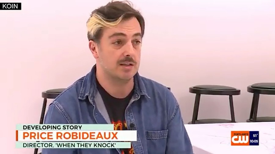 A man with a mustache and streaked hair, wearing a denim shirt, is seated indoors. On-screen text identifies him as Price Robideaux, director of "When They Knock.