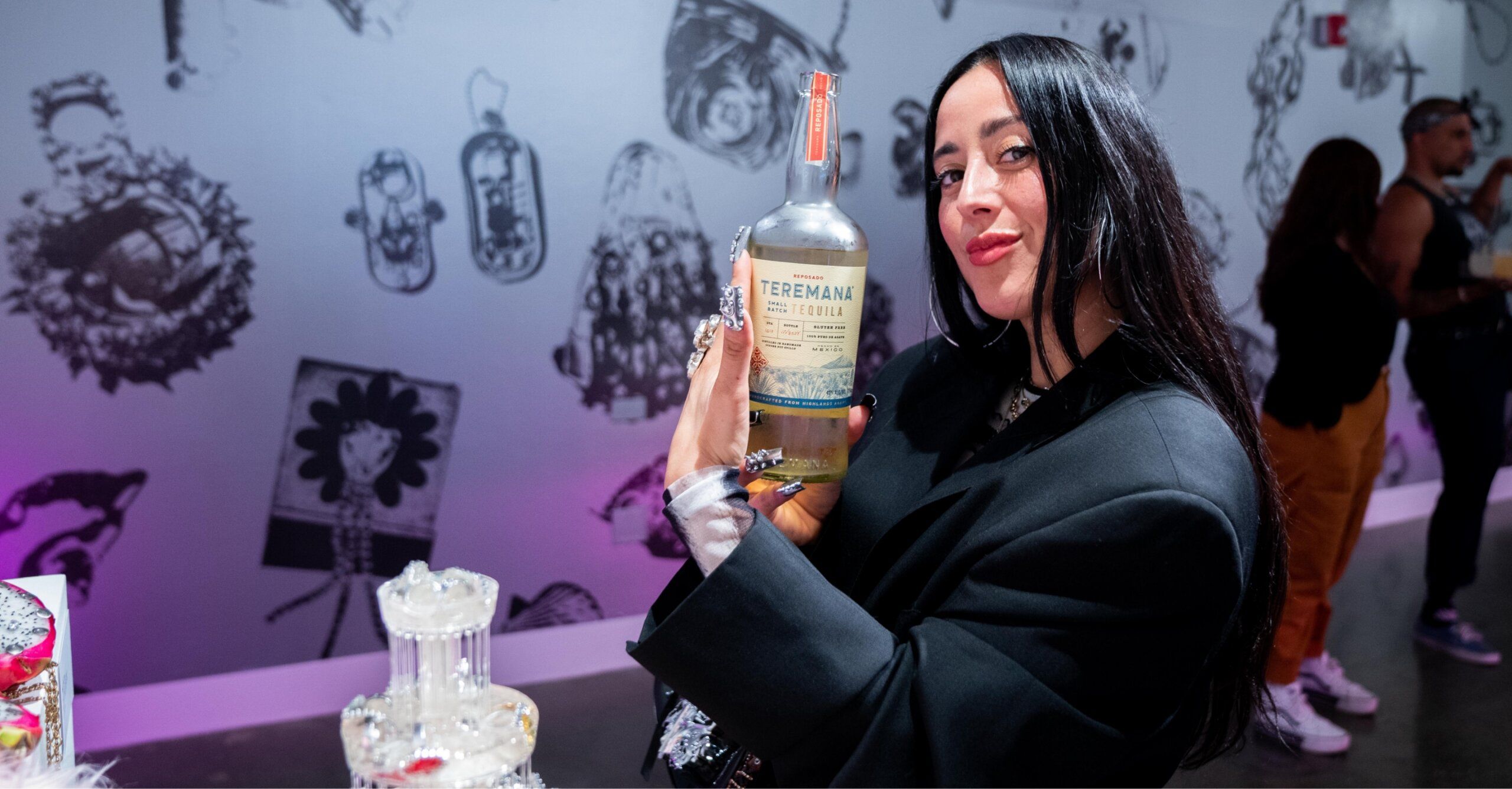 Person holding a bottle of Teremana Tequila in a room with artwork on the walls.