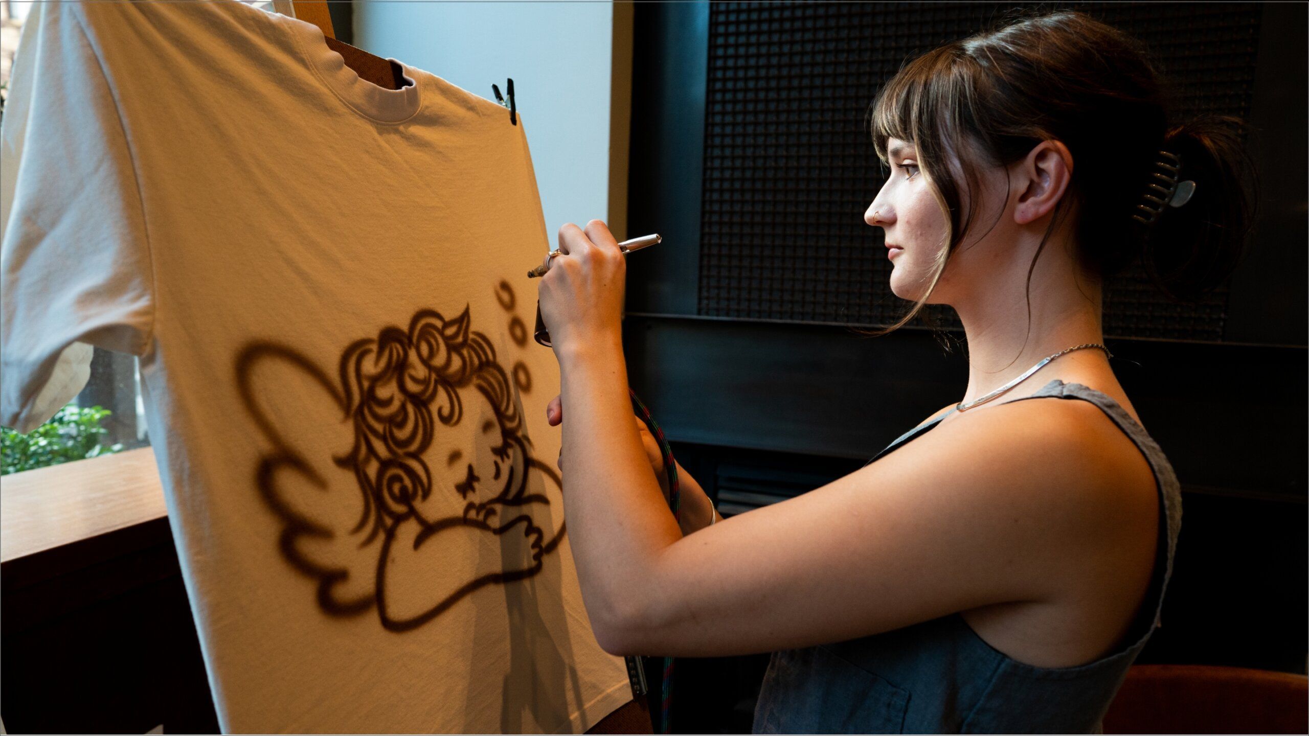 A woman is drawing on a t - shirt.