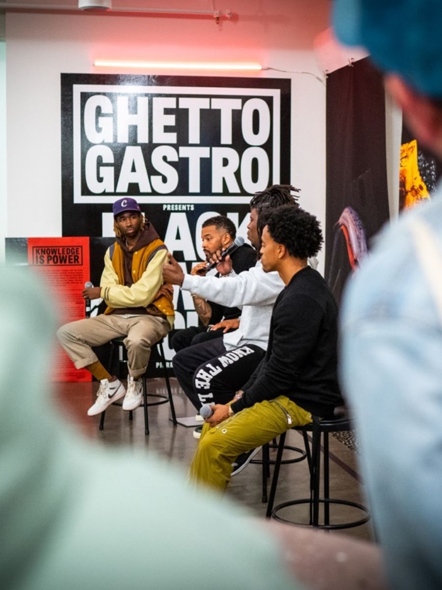 Ghetto Gastro authors and moderator speaking to crowd sitting on stools with microphones