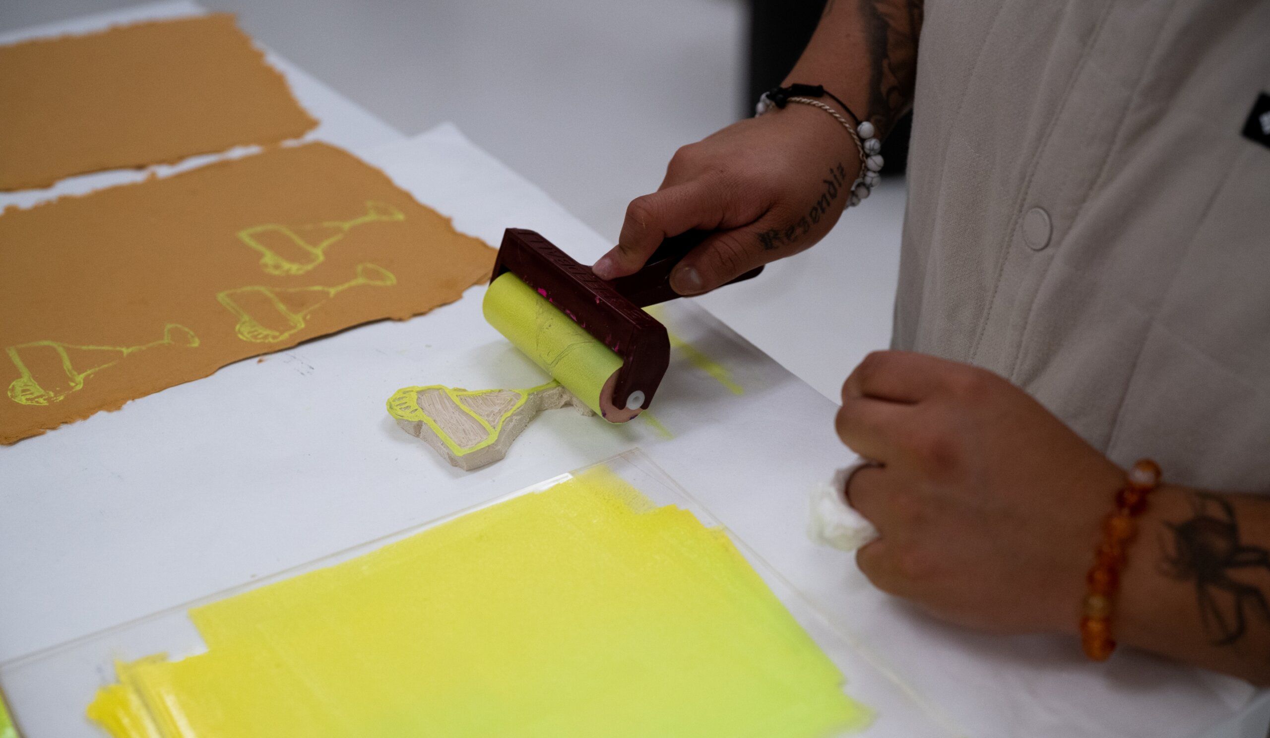 A person using a yellow paint brush on paper.