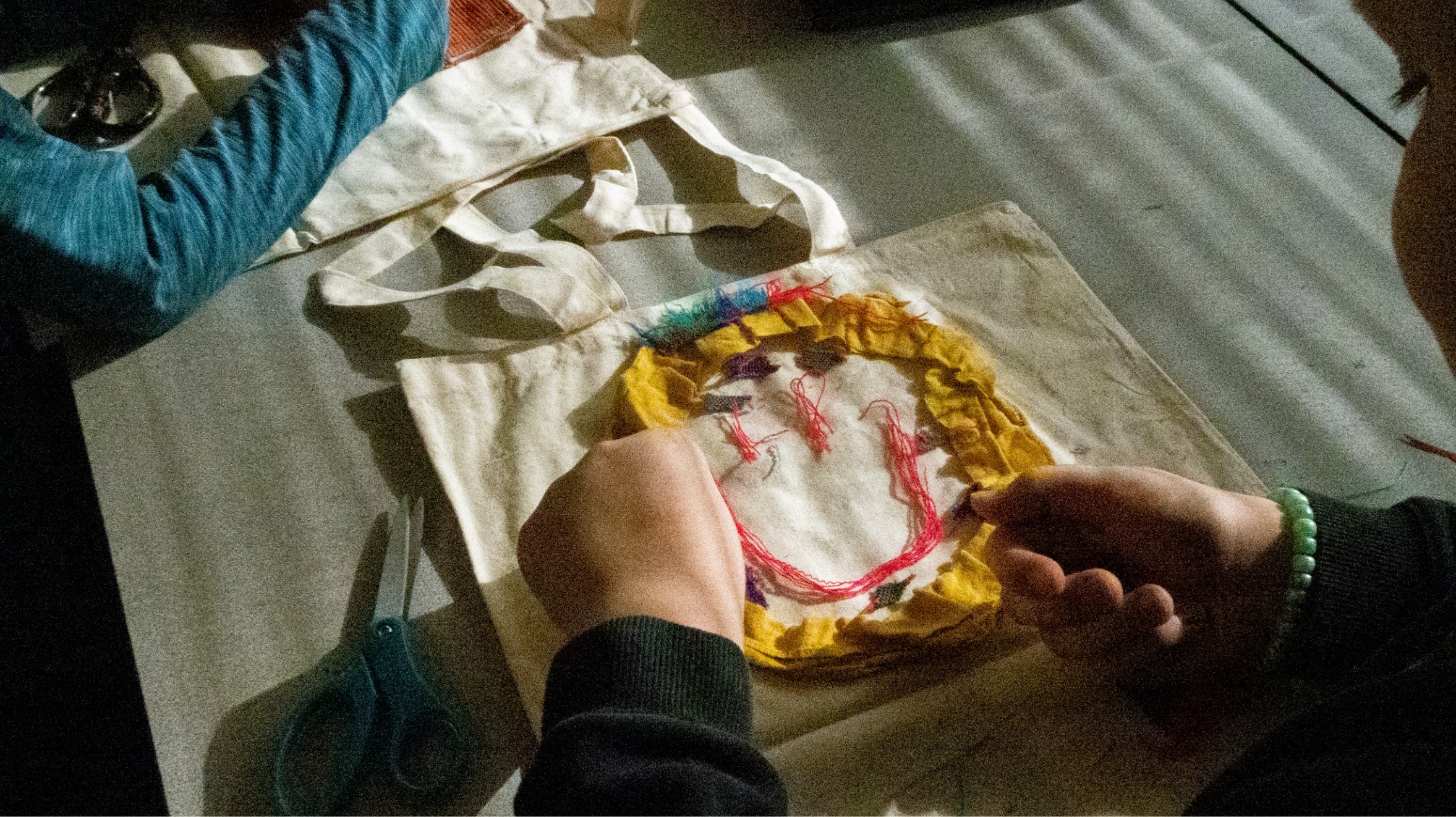 a young person lays out fabric in shape of smiley face on tote bag