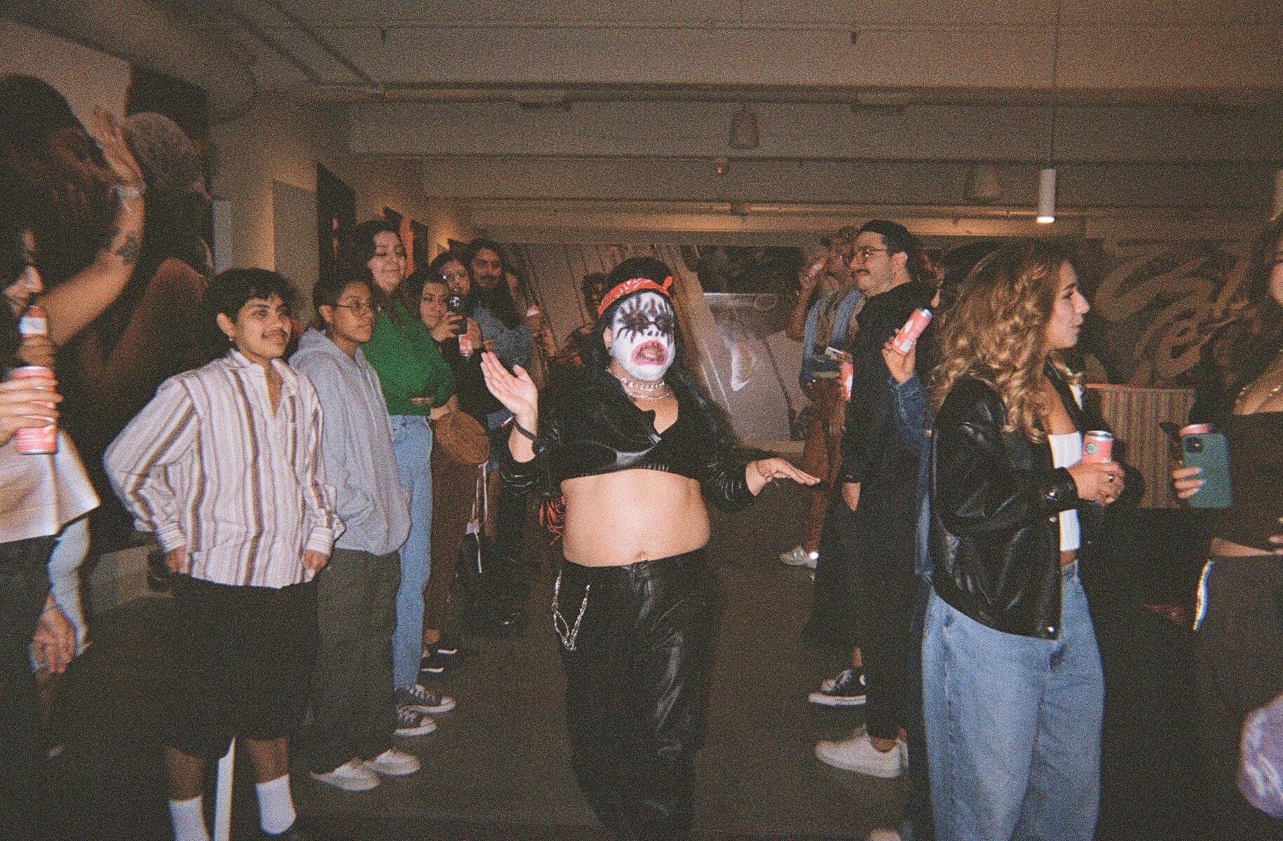 Drag performer dances in art gallery between groups of people