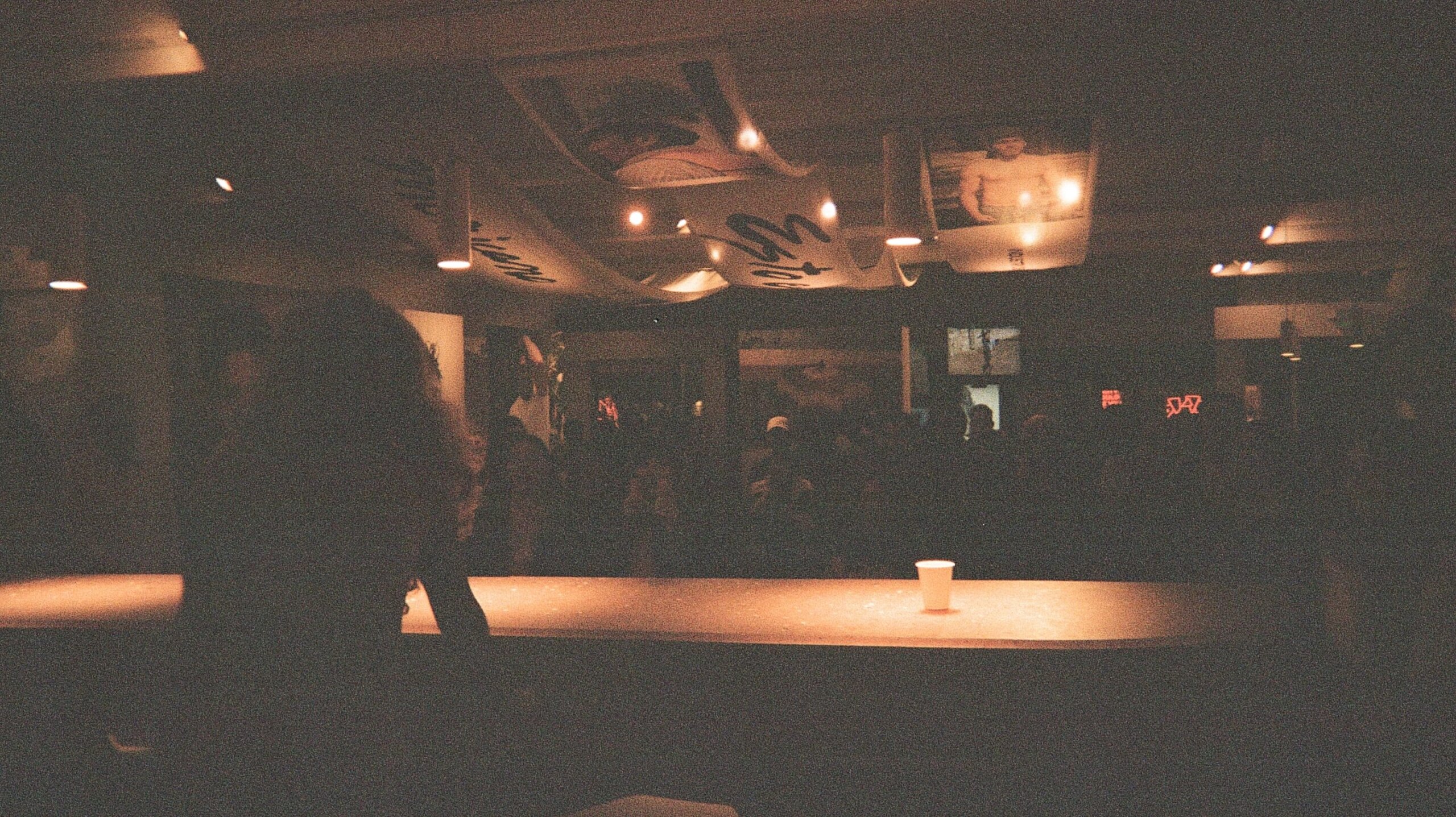 Industry One galler dimly lit with counter top visible as well as art banners in ceiling