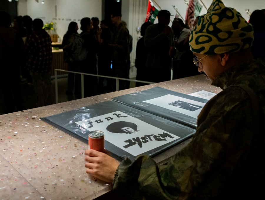 Man looks at bindeer of prints on tabletop in art gallery. Print says funk system