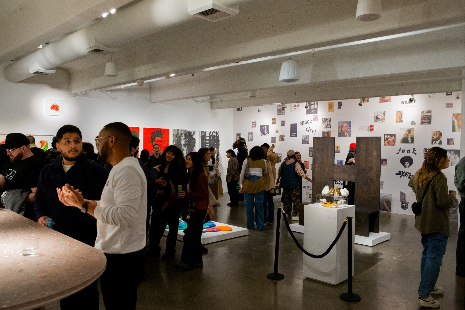 large group of people look at art and socialize in art gallery space during opening event