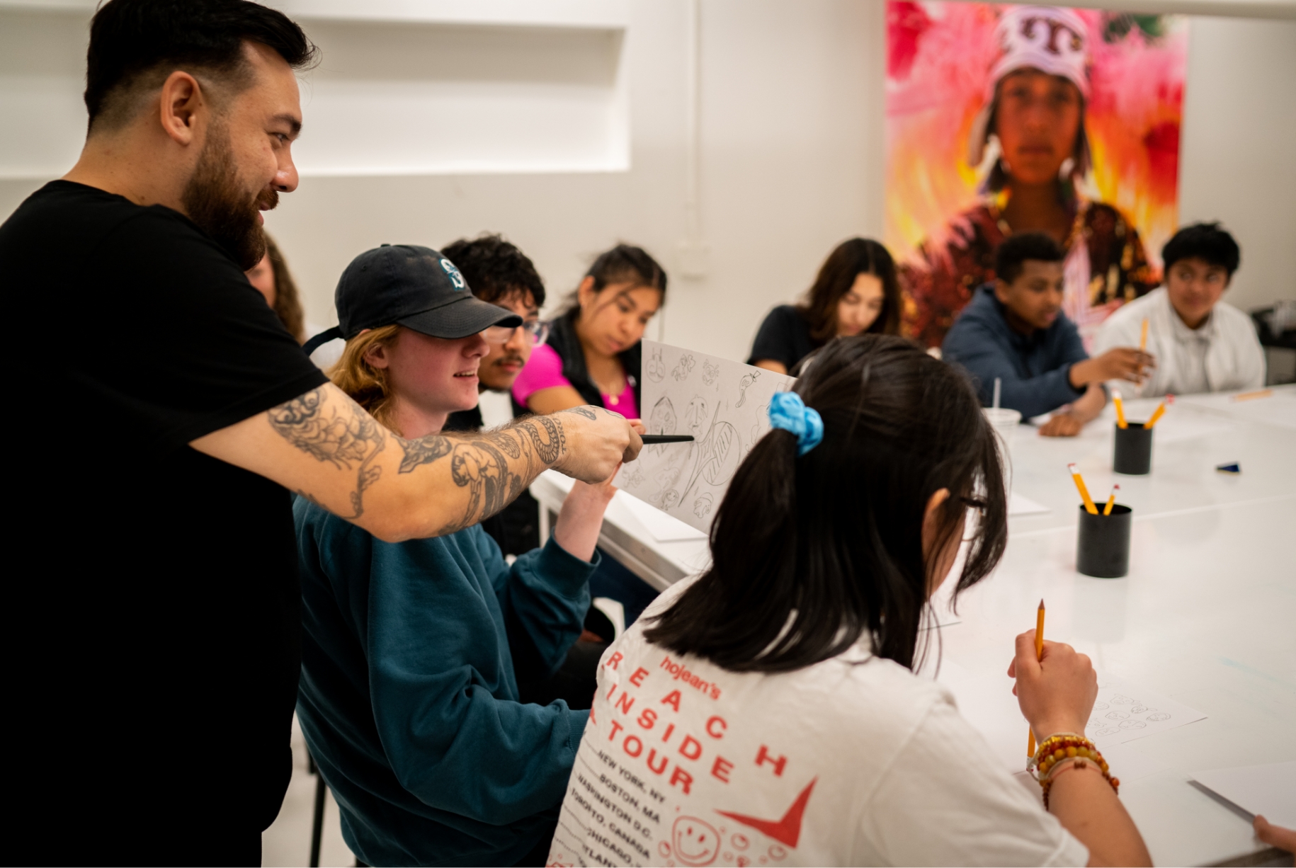 A teacher showing a drawing to a diverse group of students during a classroom session.